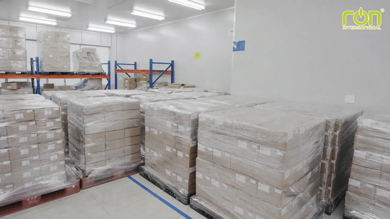 Các thùng carton quấn màng nhựa được xếp trên pallet và kệ trong kho.