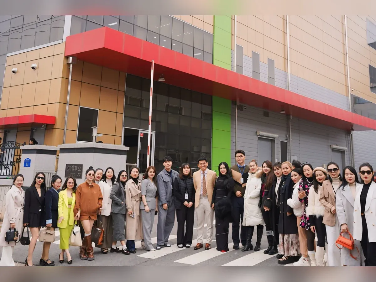 Nhóm người chụp ảnh trước tòa nhà có mái đón màu đỏ và cột màu xanh.